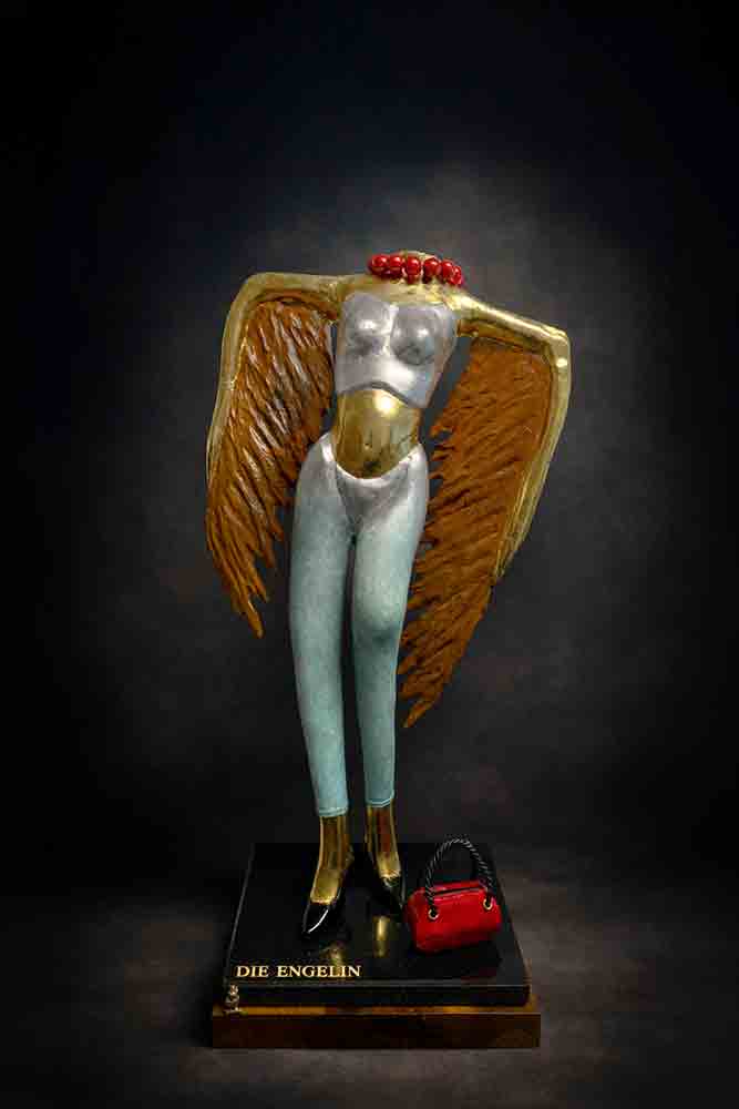 Die Engelin – Skulptur von Dieter Speth Skulptur „Die Engelin“ von Dieter Speth: moderne Engel-Figur mit goldenen Flügeln, silbernem Oberkörper und patinierten Beinen auf schwarzem Sockel mit roter Handtasche